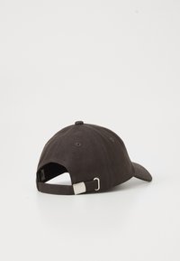 Dark brown cap made of cotton, featuring a curved brim, adjustable back strap with metal hardware, and a soft, textured finish.
