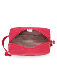 Pochette Kipling con zip di colore rosso brillante, realizzata in tessuto morbido. Include una tracolla e un interno foderato con etichetta del logo.