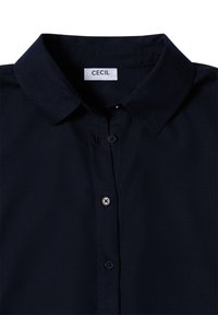Marinblå knapp-up skjorta med klassisk krage, mjuk textur och en etikett som visar "CECIL." Har fyra framknappar och subtila sömmar.
