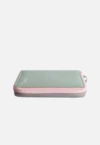 Green and pink zippered pouch featuring a smooth exterior, rounded shape, and grey base, with stitching accents and a logo on top.