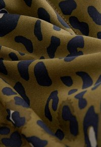 Pruun ja must leopardimuster kangas, millel on sile tekstuur, featuring ebaühtlased mustad laigud oliivrohelisel taustal, veidi kortsus.