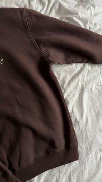 Rjava jopa z okroglim izrezom. Ima rebrast rob in manšete. Gladek material, minimalističen dizajn in majhna etiketa na strani.