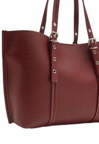 Burgundowa torba na ramię wykonana z perforowanego materiału syntetycznego. Wyposażona w podwójne uchwyty, srebrne detale i wyraźne przeszycia, które dodają tekstury.