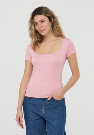 Top rosa a maniche corte con scollo quadrato, realizzato in materiale elastico. Abbinato a jeans blu larghi, creando un look casual.