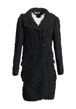 Conjunto negro texturizado de chaqueta de manga larga y falda con detalles de tela arrugada y gran solapa, aislado sobre fondo blanco.