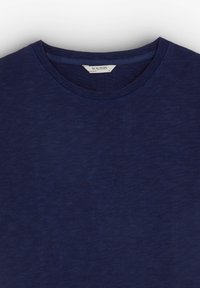 T-shirt in cotone blu navy con scollo rotondo e un logo "SCALPERS" ricamato sul petto, caratterizzato da un tessuto morbido e testurizzato.