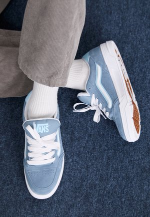 Sneakers in suede blu chiaro con lacci e dettagli bianchi, caratterizzati da una punta stretta e una suola in gomma spessa con battistrada testurizzato.