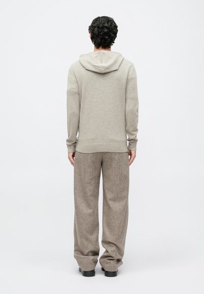 Beige hoodie med snoretræk, lange ærmer og tætsiddende manchetter, parret med løstsiddende, strukturerede brune bukser. Enkel, glat stof.