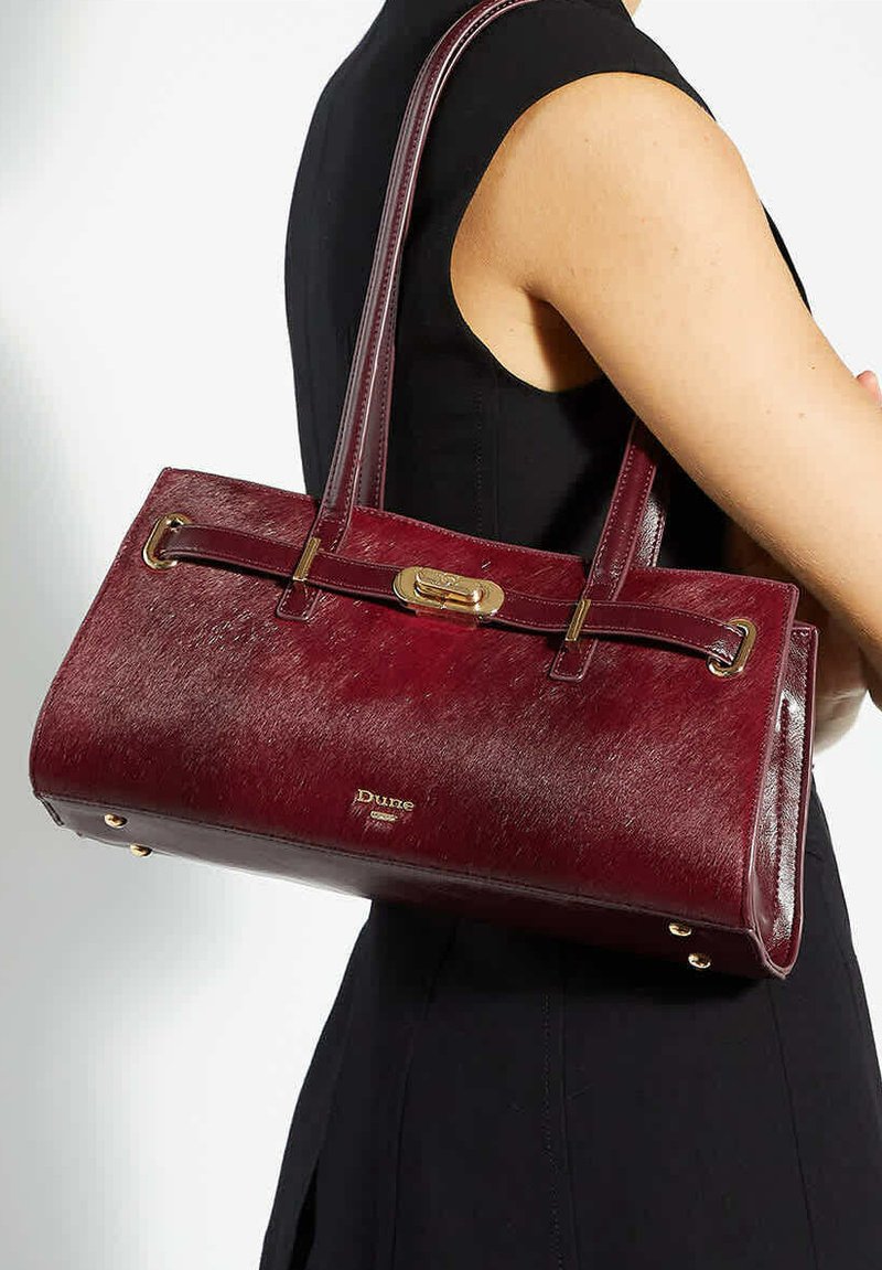 Burgundy leather handbag with a textured finish, dual top handles, gold-tone hardware, and a clasp detail at the front.