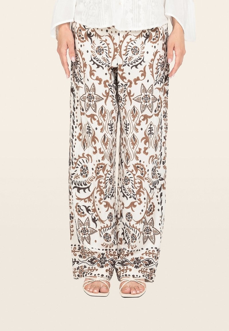 Wijdvallende broek van witte stof met een bruin en zwart bloemenpatroon. Ontworpen met een elastische tailleband en zijzakken.
