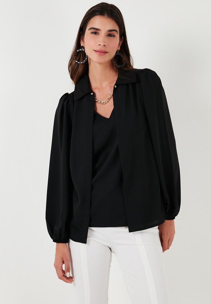 Black blouse featuring puffed sleeves, a collar, and a button front. The fabric is smooth with a subtle sheen, paired with a simple necklace.