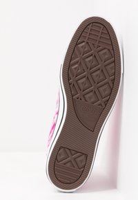 Podešev růžových tenisek Converse All Star s batikovaným vzorem, ukazující hnědou běhounovou texturu a logo na bílém pozadí.