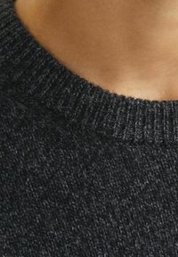 Pull en maille noire avec un col côtelé, présentant une finition texturée et douce. Gros plan sur la zone du col.