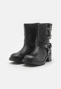 Botines de cuero negro con puntera redondeada, dos correas ajustables con hebillas, detalles en metal plateado y un tacón bajo en bloque.