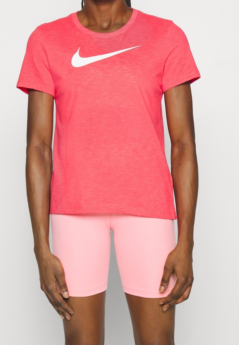 Camiseta roja de manga corta de Nike con un logo blanco Swoosh en la parte delantera, combinada con pantalones cortos de bicicleta rosas, con una textura suave y lisa.