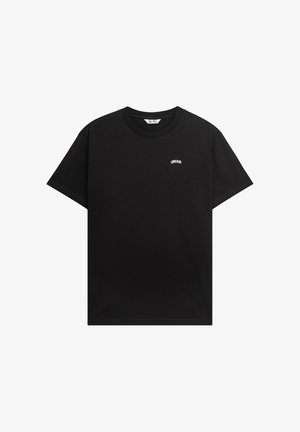 Black cotton t-shirt with short sleeves, featuring a crew neck and white "UNFAIR" text logo on the left chest. Smooth texture and relaxed fit.