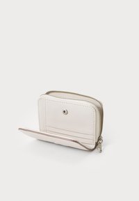 Piccolo portafoglio con zipper in morbido materiale beige chiaro, con un pulsante a scatto visibile, svariati slot per carte e una superficie liscia.