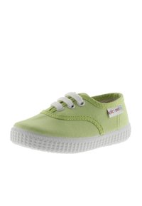 Zapatillas de lona verdes con suelas y cordones de goma blanca. Presenta una etiqueta de logo en el lateral. Textura suave y diseño de punta redonda.