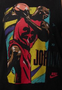 Camiseta sin mangas negra con un gráfico colorido de un jugador de baloncesto con una camiseta roja con el número 23, además de detalles en amarillo y azul.