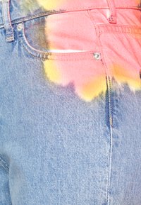 Jeans de ganga em azul claro com um design de tie-dye em degradê nas cores rosa e amarelo; inclui bolsos padrão e detalhe em botão metálico.