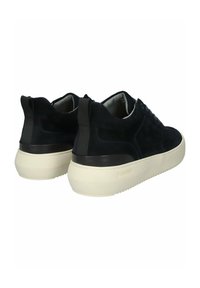 Paire de baskets en daim noir avec semelles épaisses blanc cassé vues de dos, dotées de languettes de maintien et d'un design à lacets.