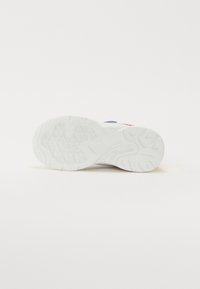 Baltā sporta apavu zole ar teksturētu profilu, kas veidota ar izliekta raksta līnijām un gludu apdari, domāta saķerei un atbalstam.