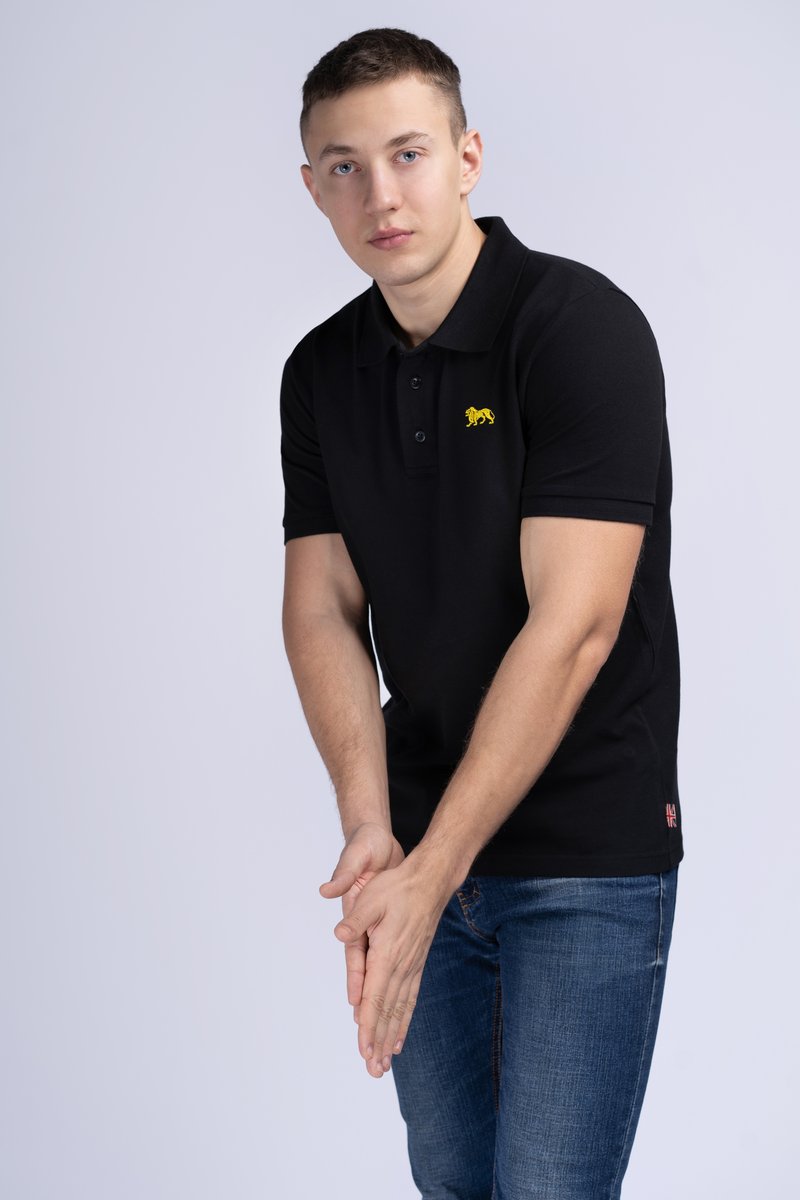 Čierne polo tričko s malým žltým logom leva; má golier, tri gombíky a krátke rukávy. Nosené s modrými džínsami.