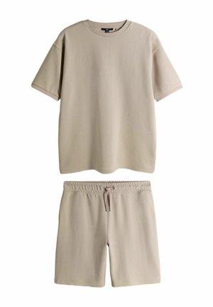 Beige short-sleeve ribbed T-shirt paired with matching drawstring elastic waist ribbed shorts.