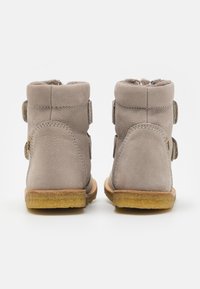 Bottes chelsea en suède tan avec une finition texturée, dotées de deux sangles réglables, d'une doublure douce et d'une semelle en caoutchouc pour une bonne adhérence.