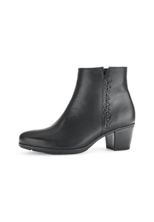 Bottine en cuir noir avec un bout arrondi, un talon modéré, et des détails en clous décoratifs sur le côté. Texture lisse et design épuré.