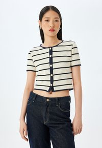 Cardigan corto a maniche corte in crema con strisce blu, dotato di grandi bottoni, scollatura rotonda e un motivo di maglia testurizzato.