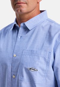  Lichtblauw button-up shirt van katoen met een zak en een geborduurd logo. Beschikt over een klassieke kraag en een standaard pasvorm.