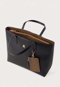 Sort faux læder tote bag med guld hardware, lynlåslukning og en aftagelig brun kortholder. Indvendigt har den en kontrasterende beige foring.