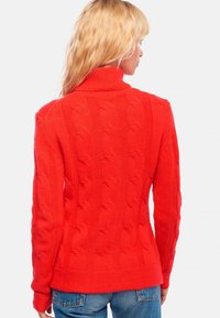 Pull en tricot rouge avec un col montant, motif en relief, ourlet et poignets côtelés, et une coupe ajustée. Vue arrière montrée.
