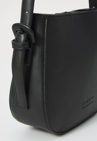 Borsa a spalla in pelle nera con una texture liscia, forma rettangolare, tracolla regolabile e un sottile dettaglio di branding sul davanti.