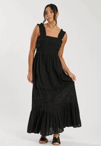 Svart maxi-klänning med volangärmar, fyrkantig halsringning och broderade hålmönster. Flödande kjol med en tvåskikts nederkant.