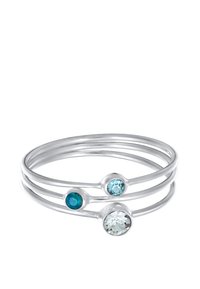 Tre sammenlinkede sølvringe prydes af tre ovale ædelstene: en dyb blå, en lys blå og en klar, sat i glatte metalaccenter.