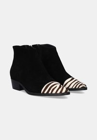 Botines de ante negro con un bajo tacón cuadrado, que presentan punteras texturizadas a rayas en crema y marrón, además de un cierre con cremallera lateral.