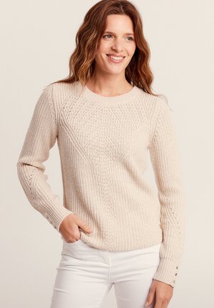 Pull en tricot beige avec un motif texturé, col rond et manches longues. Les détails comprennent des accents de boutons aux poignets.