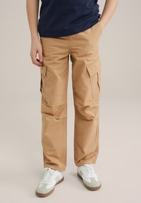 Beige cargobroek met zijzakken en een relaxte pasvorm, gemaakt van duurzaam katoen. Gecombineerd met witte sneakers.