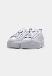Białe skórzane sneakersy z platformą, teksturowana cholewka, okrągły czubek, sznurowana konstrukcja oraz złote akcenty.