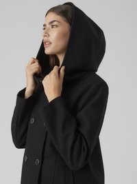 Fekete gyapjú kabát kapucnival, dupla soros kivitelben, nagy gombokkal és oldalzsebekkel. Sima textúra és testhez simuló sziluett.