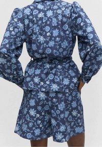 Floral print dress and shorts set in navy blue with light blue flowers, featuring long puff sleeves, a cinched waist, and a gathered back detail.