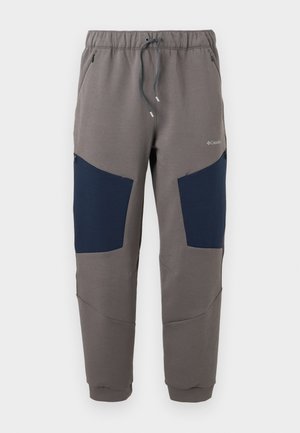 Pantalones jogger grises con paneles azul marino en las rodillas, cintura elástica, cordón ajustable, bolsillos con cremallera y logo de Columbia en el muslo superior.