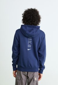 Navy blue hooded sweatshirt made of cotton blend material. Features a white printed logo and text on the back. Ribbed cuffs and hem.