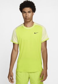 Camiseta atlética de un brillante verde lima con mangas raglán en un amarillo claro que contrastan. Presenta un pequeño logo de Nike en negro en el pecho.