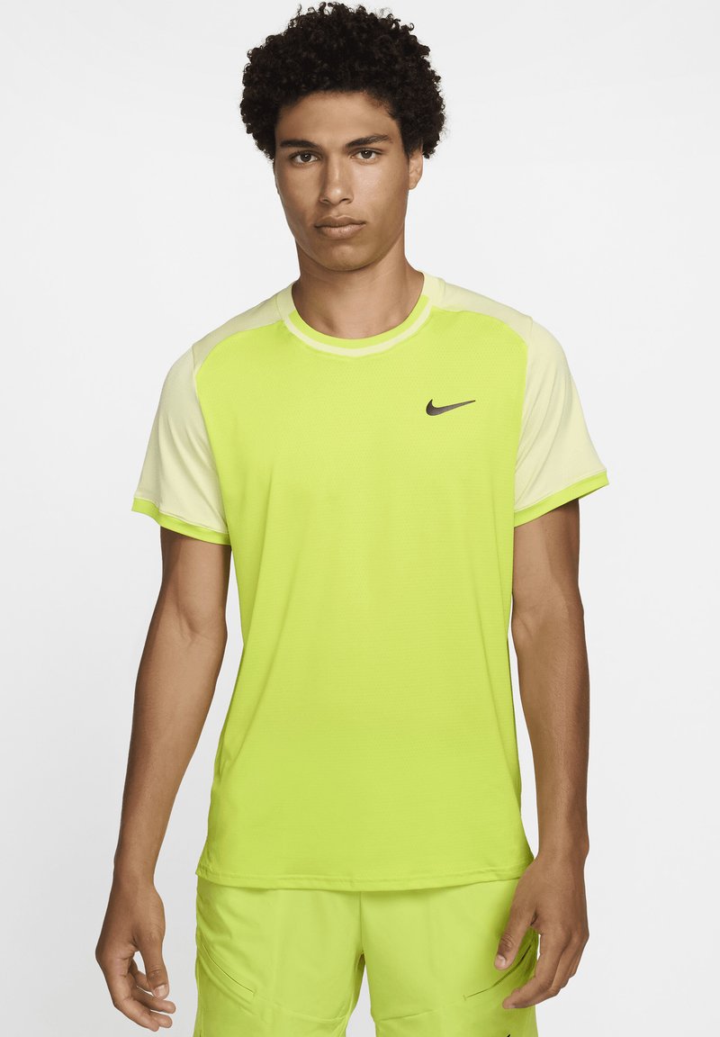 Camiseta atlética de un brillante verde lima con mangas raglán en un amarillo claro que contrastan. Presenta un pequeño logo de Nike en negro en el pecho.