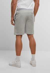 Grijze katoenen shorts met een elastische tailleband, zijzakken en een relaxte pasvorm, gecombineerd met witte sneakers en sokken tot aan de kuit.