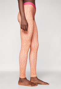 Leggings laget av elastisk stoff med et rosa mønster som har bølgete linjer på en lys oransje bakgrunn. Livbåndet er rosa.