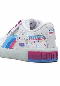 Valkoiset tennarit, joissa on sinisiä ja vaaleanpunaisia yksityiskohtia, kuppikakku-llama graafinen kuva, värikkäitä nonparelleja ja pilkullinen läpinäkyvä pohja. PUMA-brändäys näkyvissä.